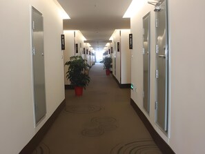 A hotel corridor with doors numbered 5007 to 5029, potted plants, and a carpet with circular patterns. - Greentree Inn Shandong Heze Caoxian Zhuangzhai Town Oriental Times City Business Hotel (Heze)