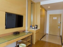 Habitación de hotel con escritorio de vidrio, televisor de pantalla plana, cafetera y puerta con un cartel.