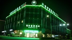 Un edificio con fachada iluminada en verde y un logotipo circular en la parte superior.