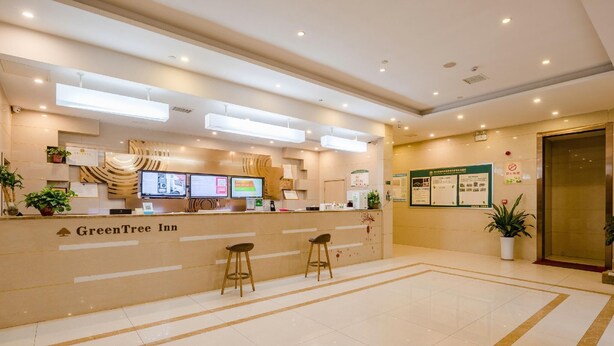 A reception area with a counter, two stools, and a sign for GreenTree Inn. - Greentree Inn Bozhou Lixin District Huishang Market (Bozhou)