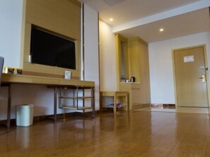 A room with a wooden floor, a desk, a chair, a trash bin, a door, and a window. - Greentree Inn Bozhou Lixin District Huishang Market (Bozhou)