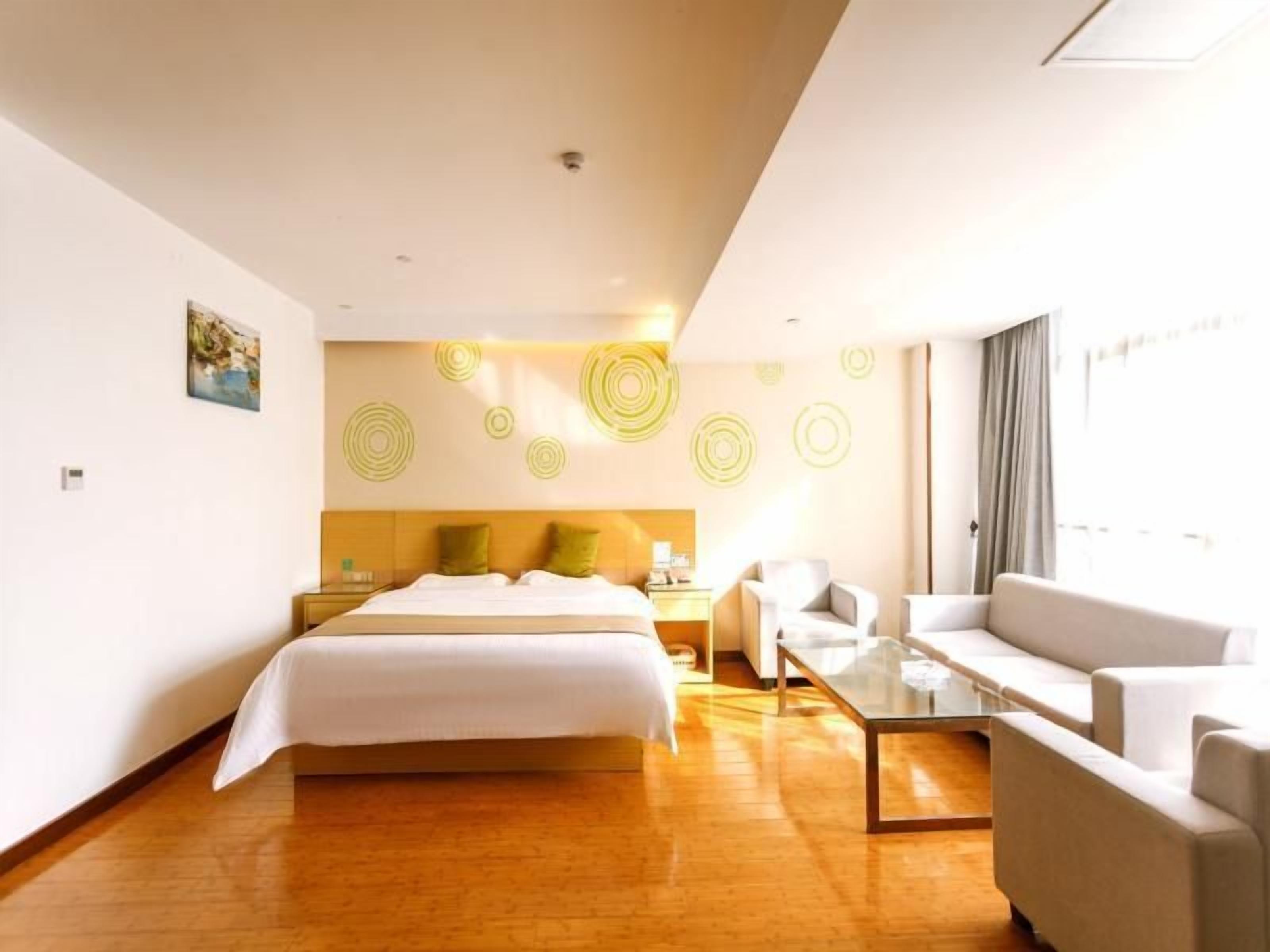 A hotel room with a bed, a sofa, a coffee table, and a wall with circular patterns.
