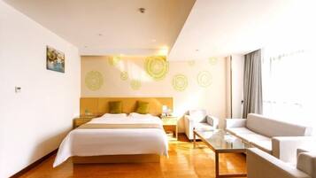 A hotel room with a bed, a sofa, a coffee table, and a wall with circular patterns.