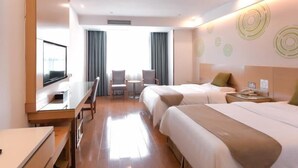 Una habitación de hotel con televisión, dos camas, escritorio y una silla.