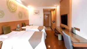 Habitación de hotel con dos camas, un escritorio, un televisor y un baño visible a través de una puerta abierta.