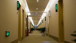 A hotel corridor with directional signs, potted plants, and a carpeted floor. - Greentree Inn Bozhou Lixin District Huishang Market (Bozhou)