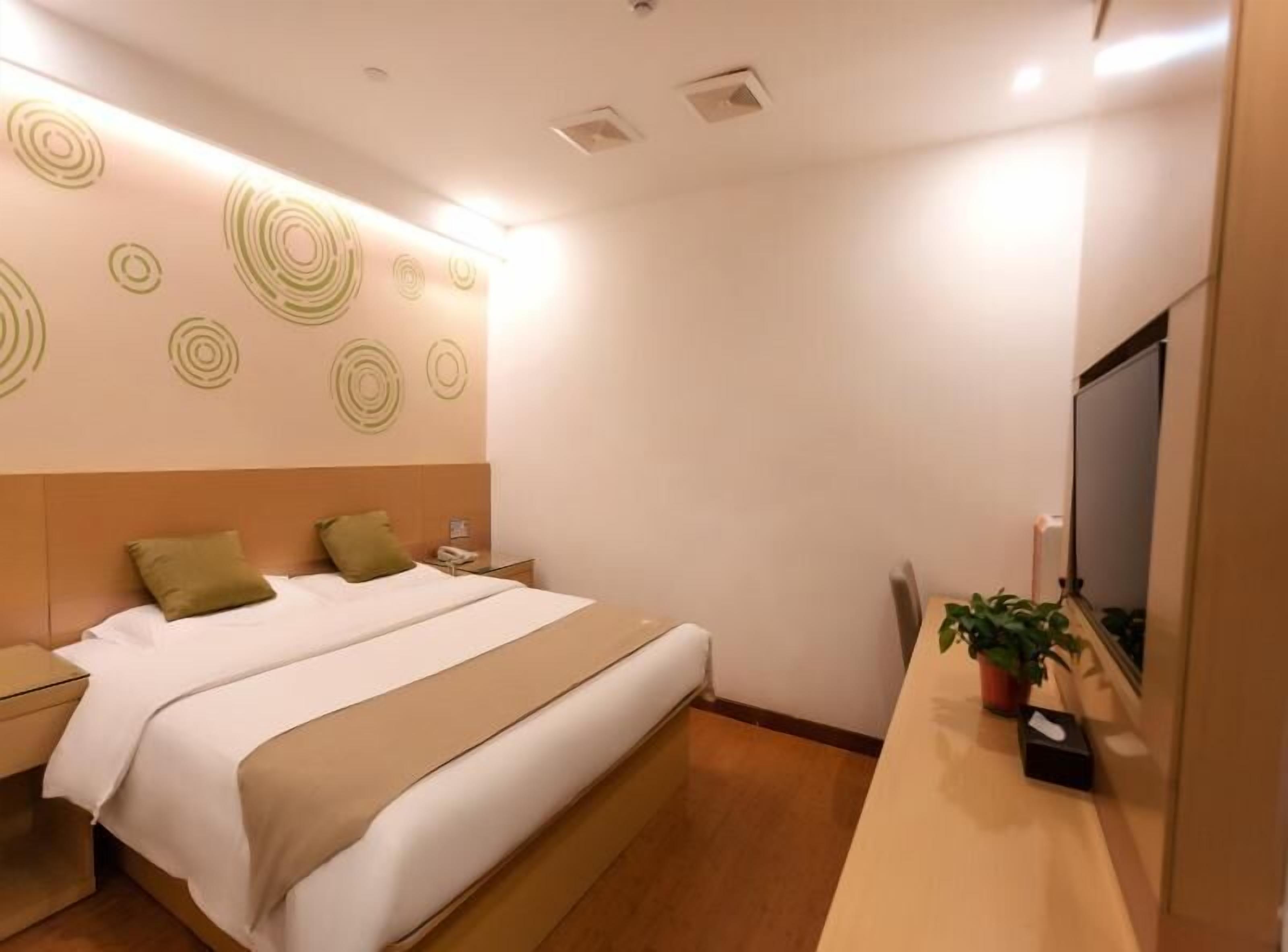 A hotel room with a bed, bedside table, and a TV.