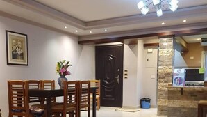 A modern dining area with a wooden table and chairs, a vase with flowers, and a patterned rug. - Charming 3-Bed Apartment in New Cairo City (New Cairo City)