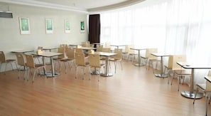 A spacious room with multiple tables and chairs, large windows with curtains, and framed pictures on the walls. - Greentree INN Huainan Jinjialing Road Oriental General Hospital (Huainan)