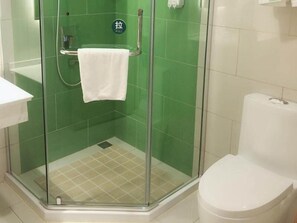 Shower area features a glass enclosure, a towel rack, and a toilet.