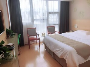 A hotel room with a bed, two chairs, a small table, and a desk with a computer and plants. - Greentree Inn Huainan Jinjialing Road Oriental General Hospital (Huainan)