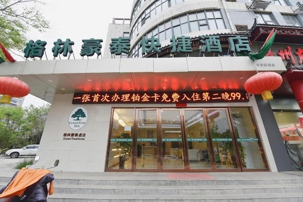 A hotel entrance with a sign in Chinese characters, a Green Tree Inn logo, and a promotional offer for a free stay. - Greentree INN Huainan Jinjialing Road Oriental General Hospital (Huainan)