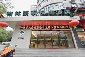 A hotel entrance with a sign in Chinese characters, a Green Tree Inn logo, and a promotional offer for a free stay.