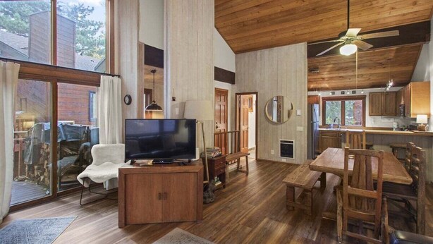 Amplia sala de estar con piso de madera, televisor y mesa de comedor con sillas.