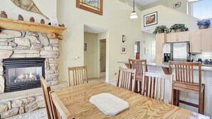 Une cuisine spacieuse avec une cheminée en pierre, une table à manger en bois et des chaises.