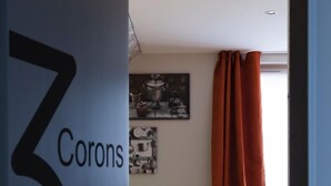 Ein modernes Zimmer mit einer Couch, einer Wand mit Kunstwerken und einer Tür mit der Aufschrift '3 Corons'.
