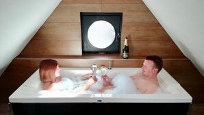 Ein Paar in einer Badewanne mit einer Champagnerflasche und Gläsern.