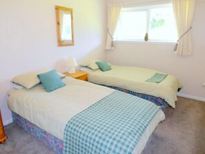 A bedroom with two beds, a window with curtains, a bedside table with a lamp, and a mirror on the wall. - Sleeps6- Countryside Privacy- 30MinToBeach (Callington)