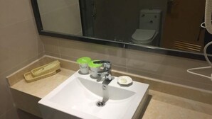 Um banheiro com pia branca, espelho e vaso sanitário. Há dois recipientes com tampa verde na bancada da pia.