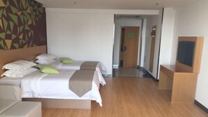 Quarto de hotel com duas camas, um sofá, uma televisão e um espelho.