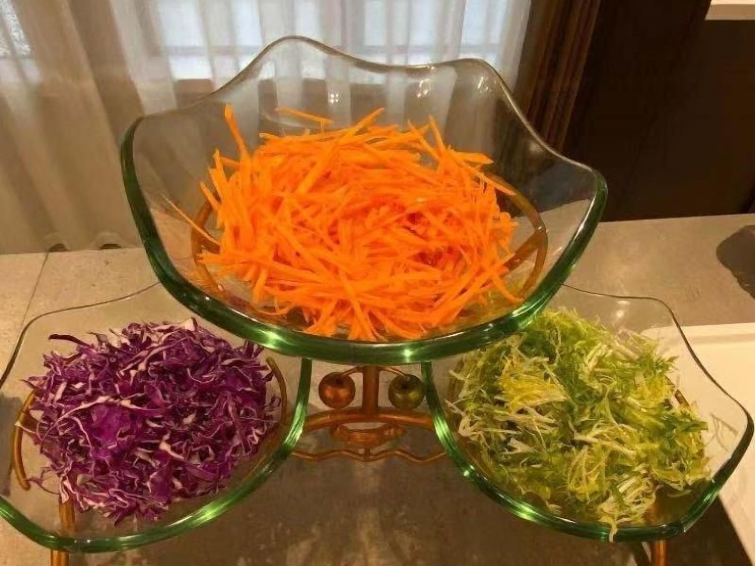 Three glass bowls on a table with shredded vegetables.