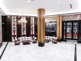A modern lobby with a central seating area, tall wooden columns, and a large window with a city view.