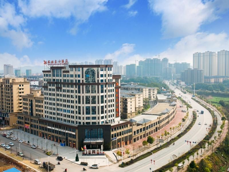 A multi-story hotel with a modern architectural design, featuring a prominent entrance and a parking area in front.