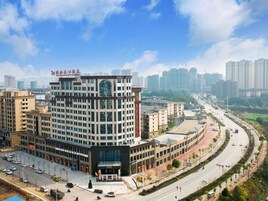 A multi-story hotel with a modern architectural design, featuring a prominent entrance and a parking area in front.