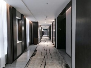 A modern hotel hallway with a long corridor, dark wooden doors, and a marble floor with a crack-like design. - Greentree Eastern Yingtan City Guixi Municipal Government Hotel (Yingtan)