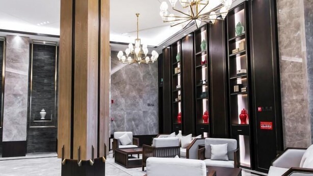 A modern lobby with a large wooden column, a chandelier, and seating areas with white cushions. - Greentree Eastern Yingtan City Guixi Municipal Government Hotel (Yingtan)