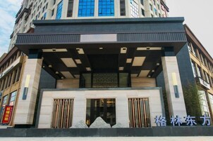Una entrada de hotel moderna con un área techada, ventanas amplias y un letrero destacado.