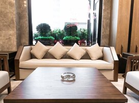 Un área de descanso moderna con un sofá, una mesa de centro de madera y vistas a un espacio exterior verde con plantas y un letrero de neón.