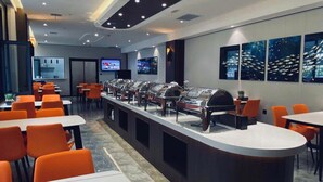 A modern restaurant with orange chairs and tables, a buffet counter with food display cases, and a large window with a view of fish swimming. - Greentree Inn Datong High Speed Railway Station Wa (Datong)