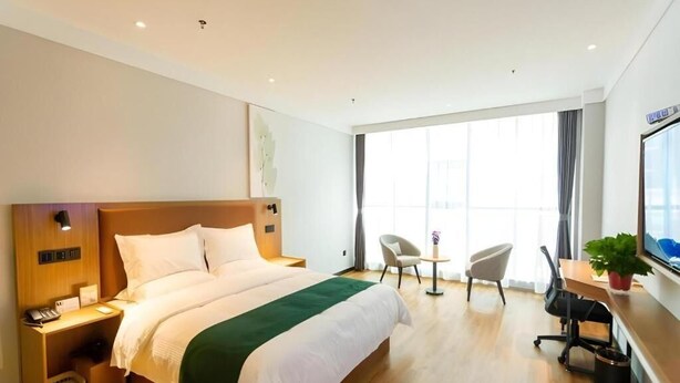 A hotel room with a large bed, a desk with a chair, a small table, and a window with curtains. - Greentree Inn Datong High Speed Railway Station Wa (Datong)