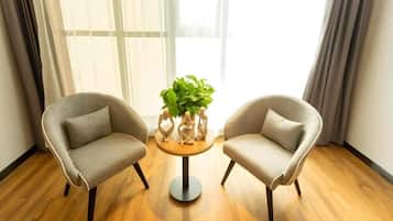 Dos sillones enfrentados con una pequeña mesa redonda entre ellos, una planta en maceta sobre la mesa, y una ventana con cortinas al fondo.