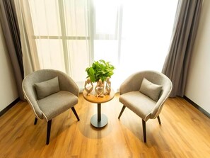 Two armchairs facing each other with a small round table between them, a potted plant on the table, and a window with curtains in the background. - Greentree Inn Datong High Speed Railway Station Wa (Datong)