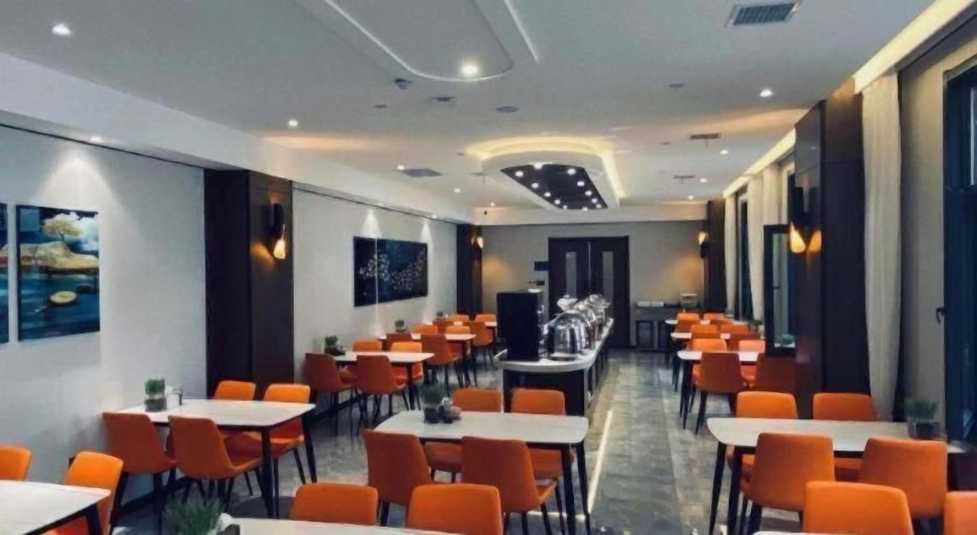 A hotel dining area with multiple tables and chairs, a buffet setup, and artwork on the walls.