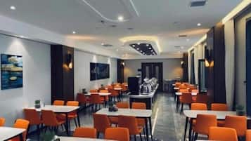 Un comedor de hotel con varias mesas y sillas, una barra de buffet y obras de arte en las paredes.