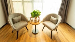 Two armchairs facing each other with a small round table in between, a potted plant on the table, and a large window with sheer curtains in the background. - Greentree Inn Datong High Speed Railway Station Wa (Datong)