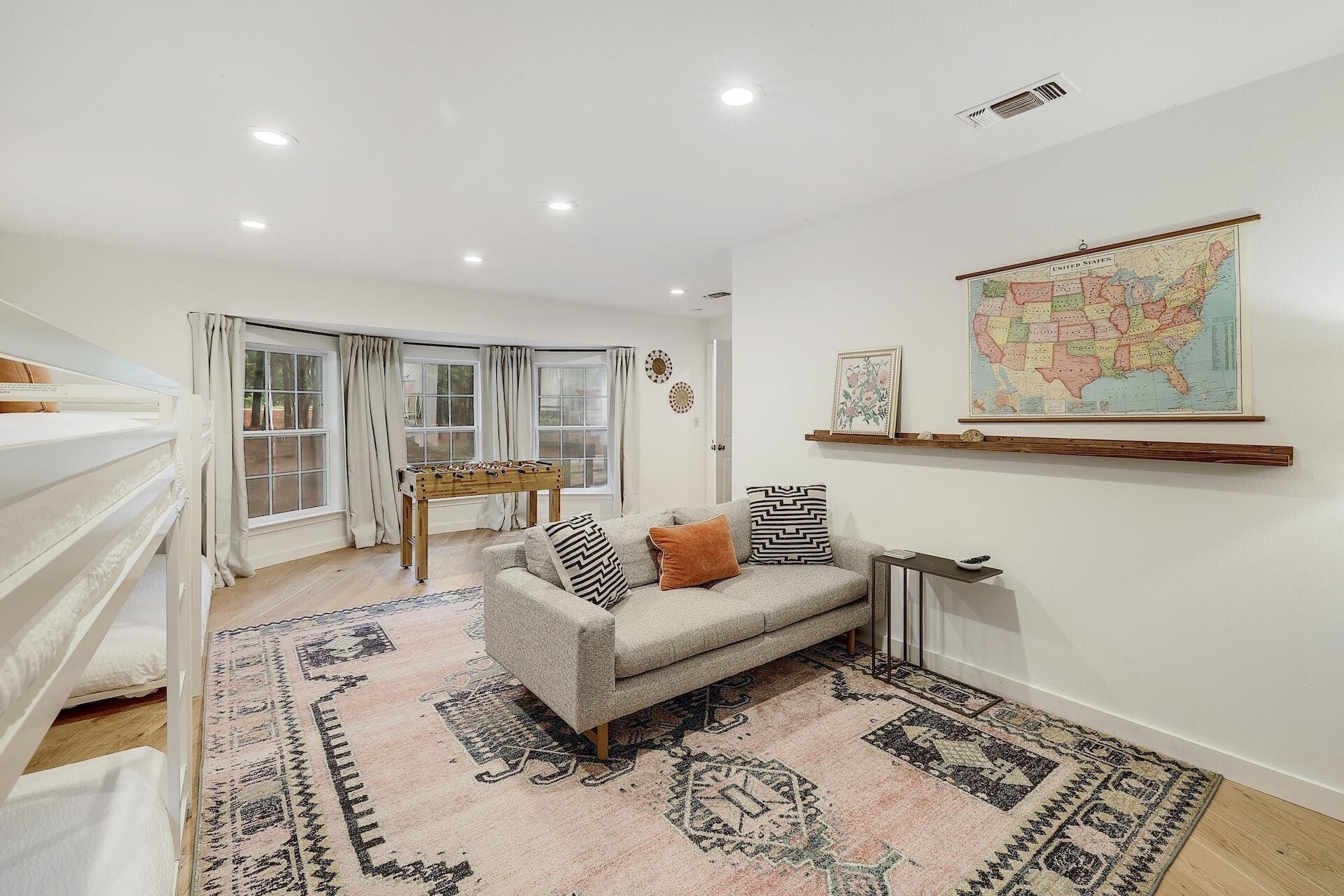 A spacious living room with a sofa, a foosball table, and a large map on the wall.