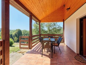 An outdoor patio with a wooden table and chairs, a view of trees, and a clear sky. - Kyjov u Krásné Lípy by Interhome (Krasna Lipa)