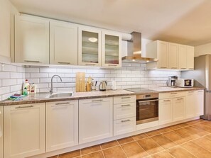 A modern kitchen with white cabinetry, a stainless steel sink, and a built-in oven.