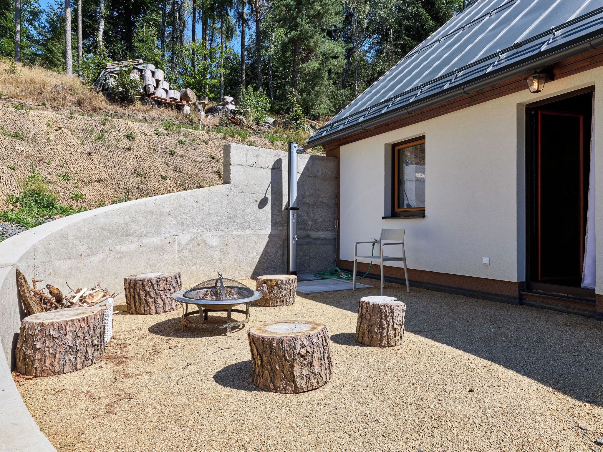 A patio area with a fire pit, seating, and a building with a window and door.