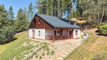 Une maison de plain-pied avec un toit en pente, une véranda en bois et une allée de gravier menant à l’entrée.