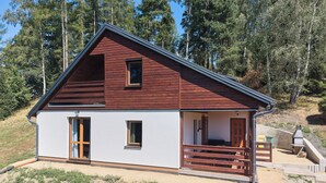 A two-story cabin with a sloped roof, a porch with wooden railings, and a small window on the upper floor. - Kyjov u Krásné Lípy by Interhome (Krasna Lipa)