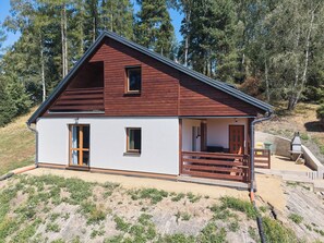 A two-story cabin with a sloped roof, a porch with wooden railings, and a small window on the upper floor. - Kyjov u Krásné Lípy by Interhome (Krasna Lipa)