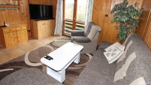 Een gezellige woonkamer met een bank, een salontafel, een televisie en een plant.