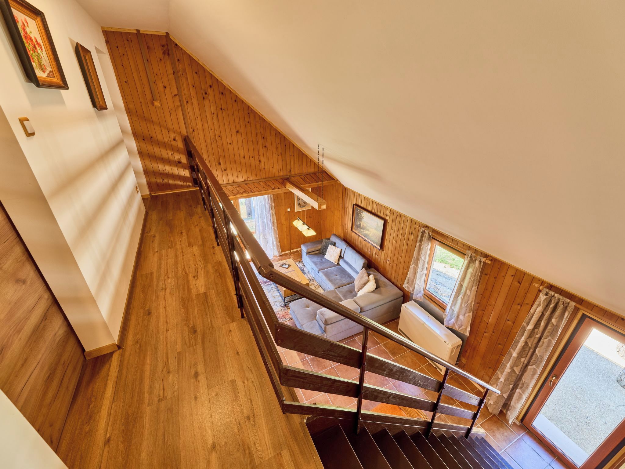 Un escalier en bois mène à un espace de vie comprenant un canapé et une fenêtre.