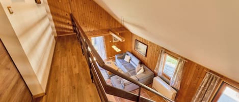 A wooden staircase leading to a living area with a sofa and a window.