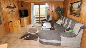 Een houten interieur met een bank, televisie en een eettafel.